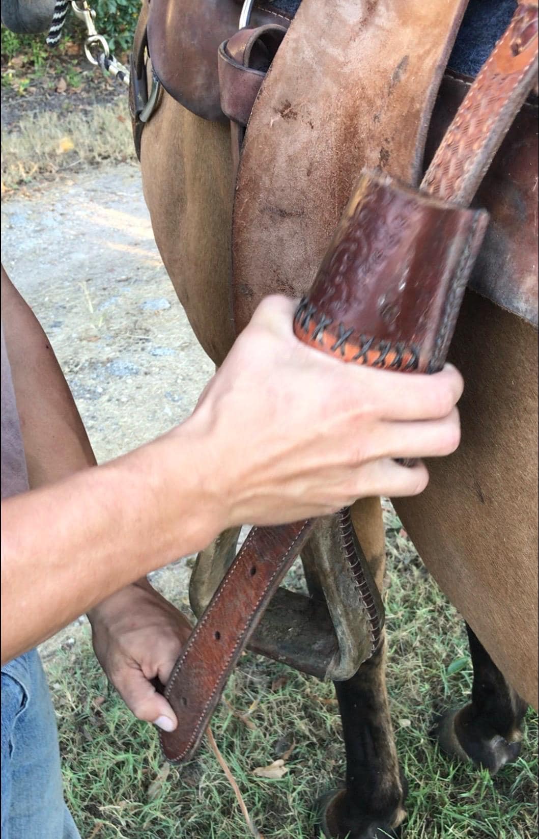 A leather bottle holder being attached to a billet strap.