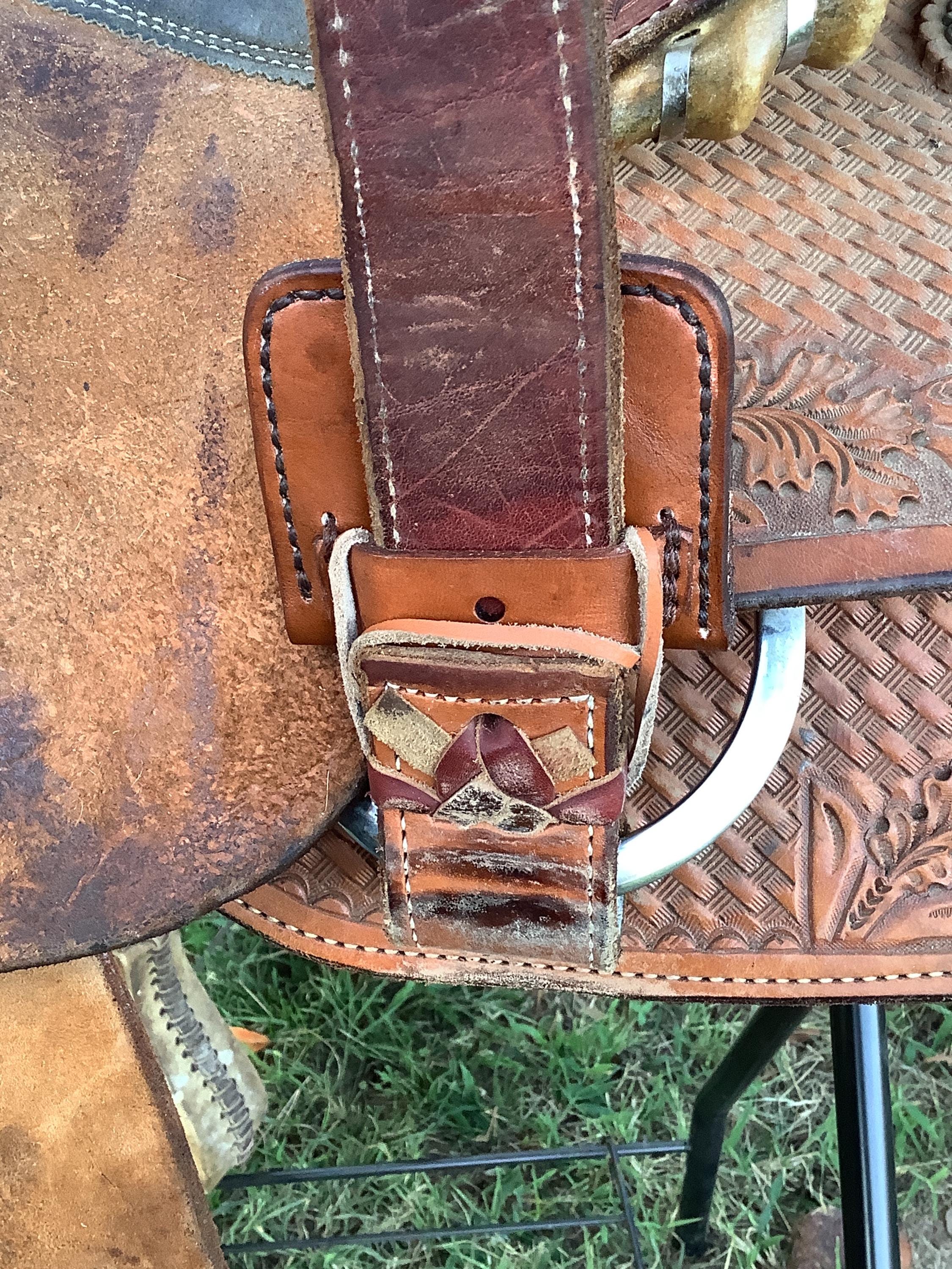 A folding hoof pick holder being attached to a saddle rear cinch.