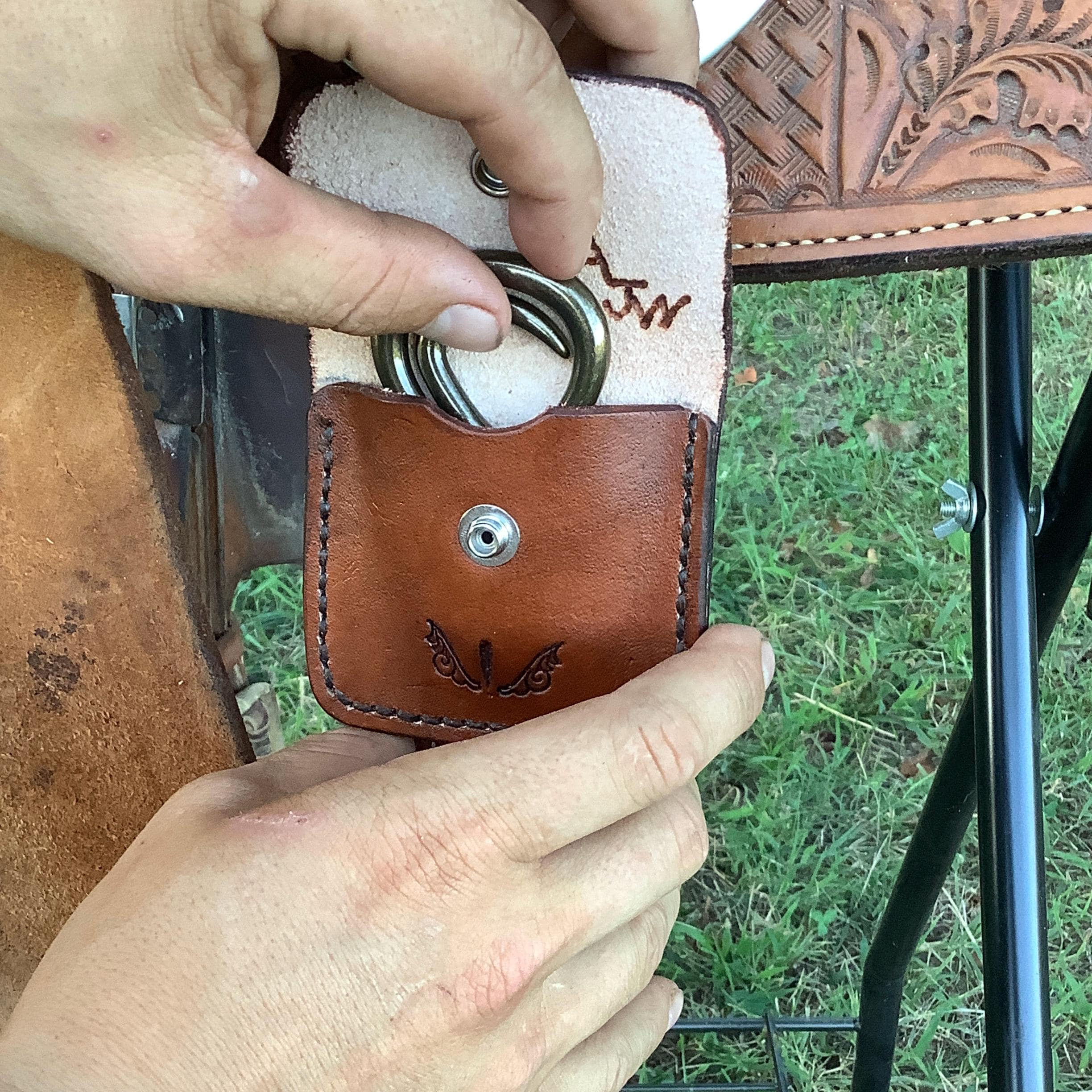 A rider taking a folding hoof pick out of a leather case.