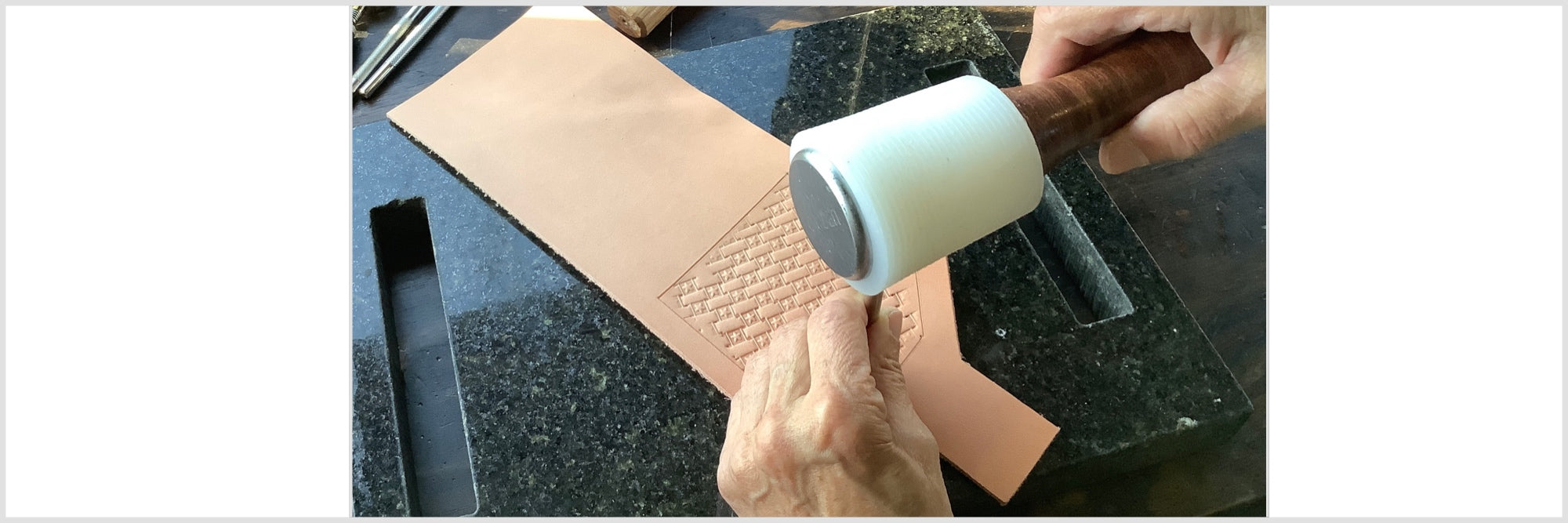 A person hand tooling basketweave leather.