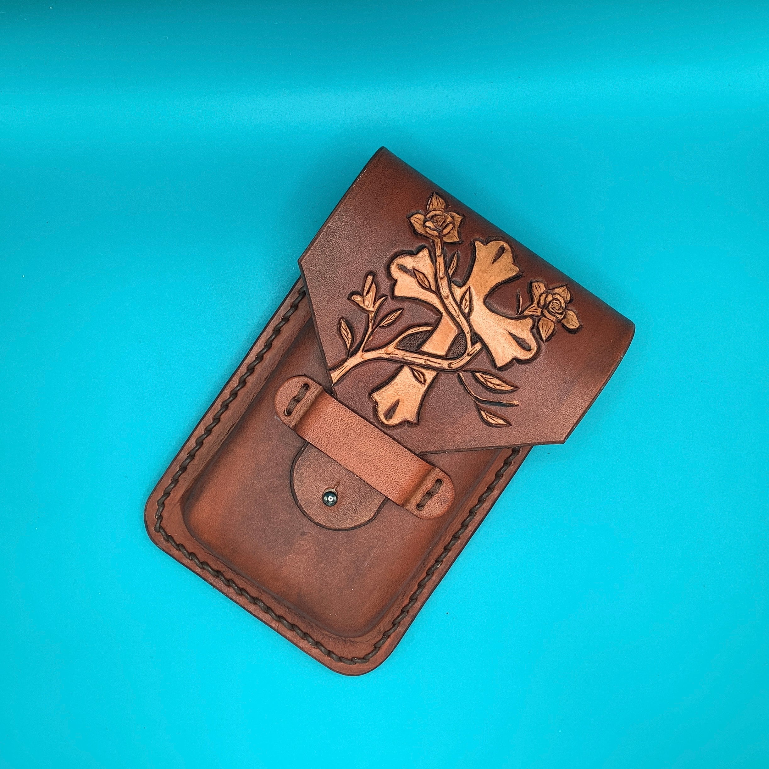 Hand tooled leather cellphone holder with cross and vine design.