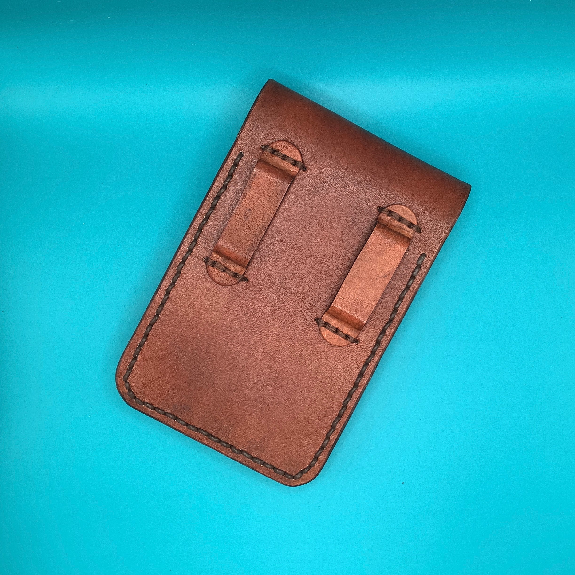 The back of a leather phone holder showing the straps that connected to a belt.