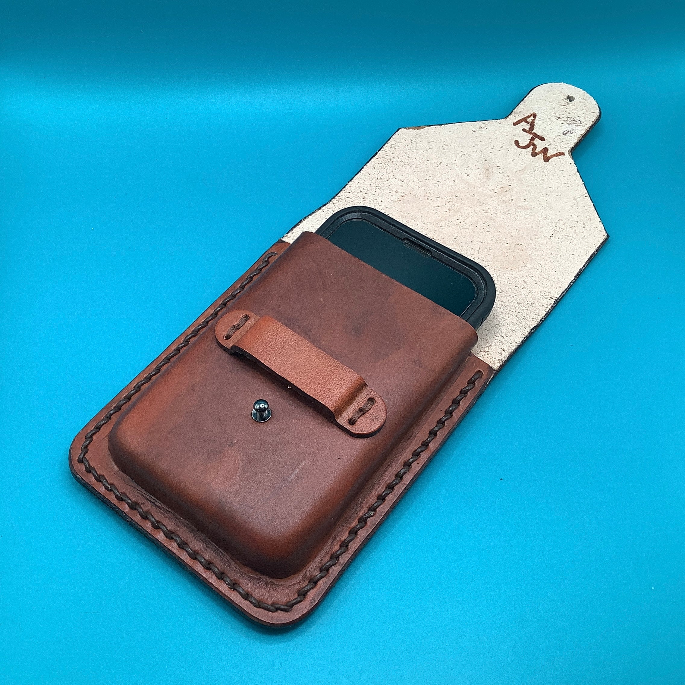 A leather phone holder showing the makers mark.