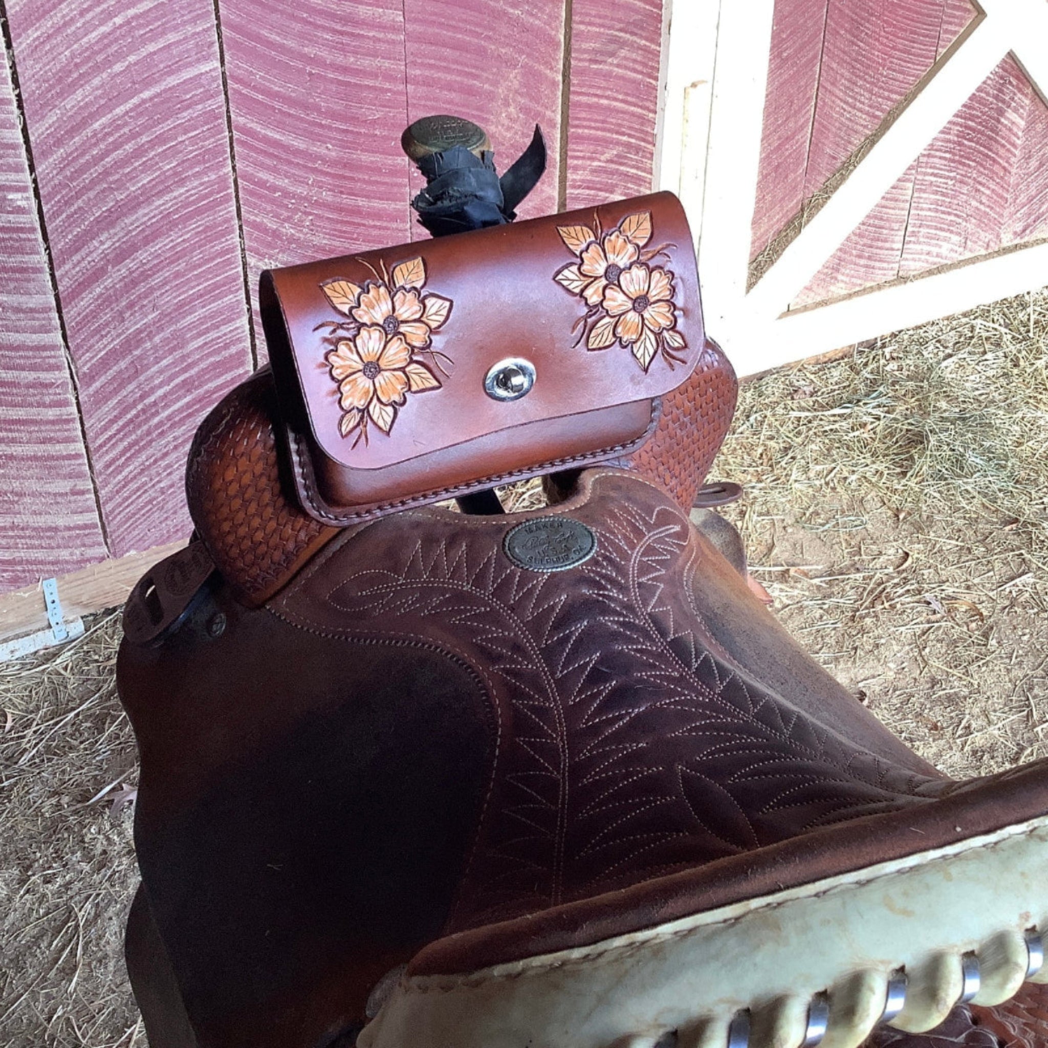 A leather pommel bag with hand tooled desert roses on a western saddle.