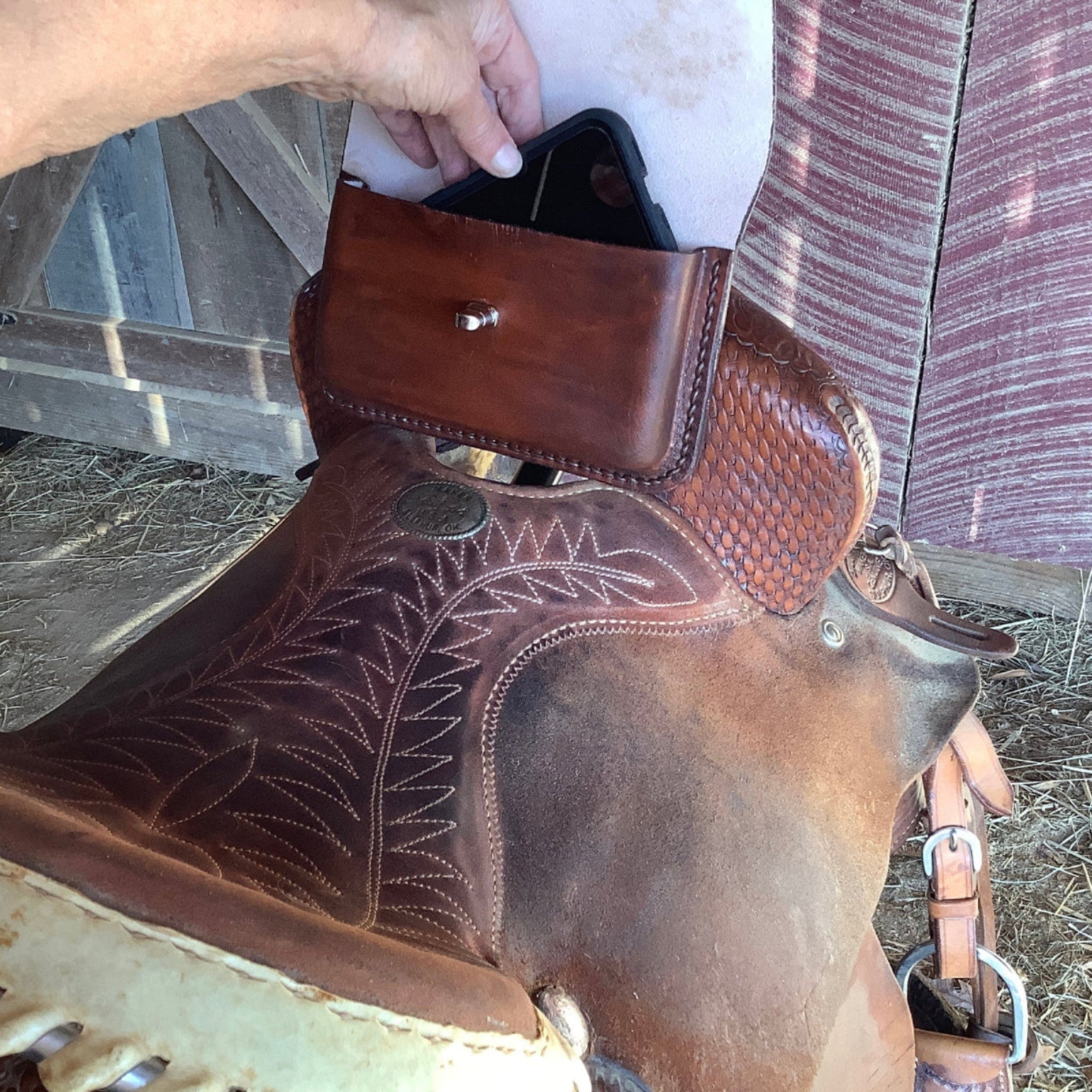 A pommel bag on a saddle being used as a cellphone holder.