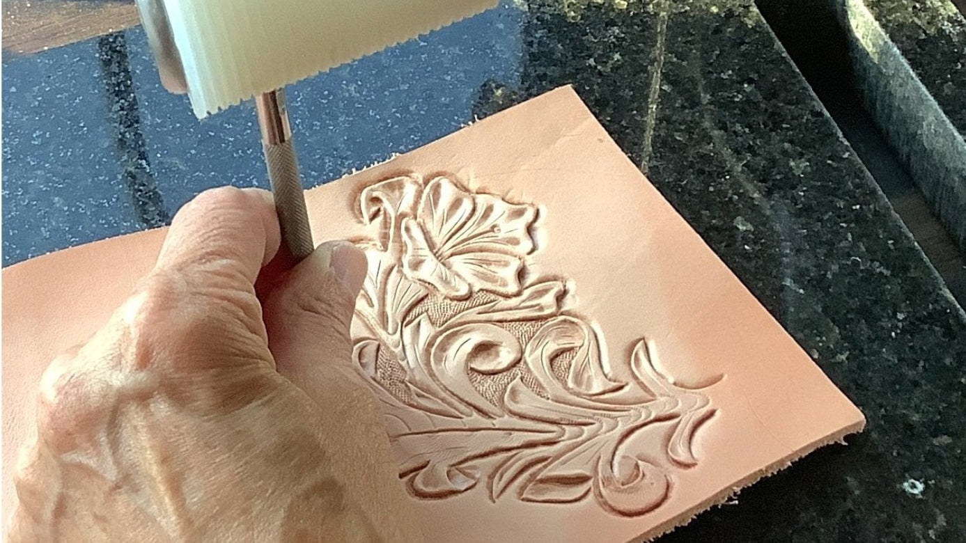 Artisan tooling leather flowers on raw leather.