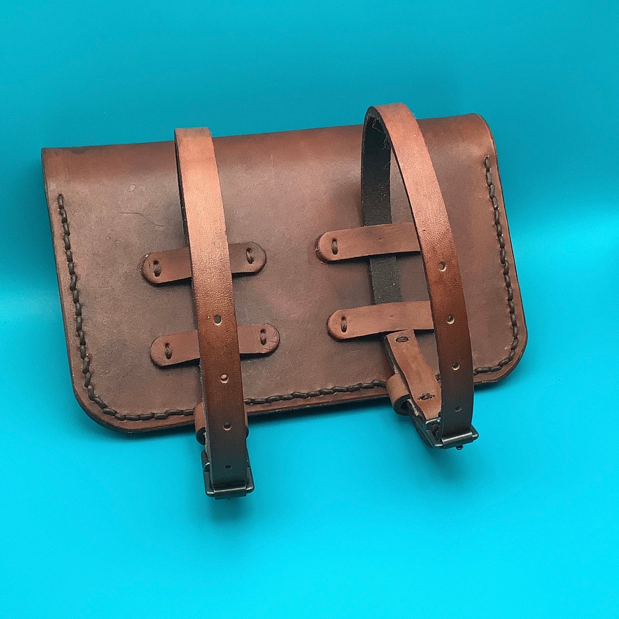 The back of a leather pommel bag for a western saddle showing the straps that attach it to the pommel.