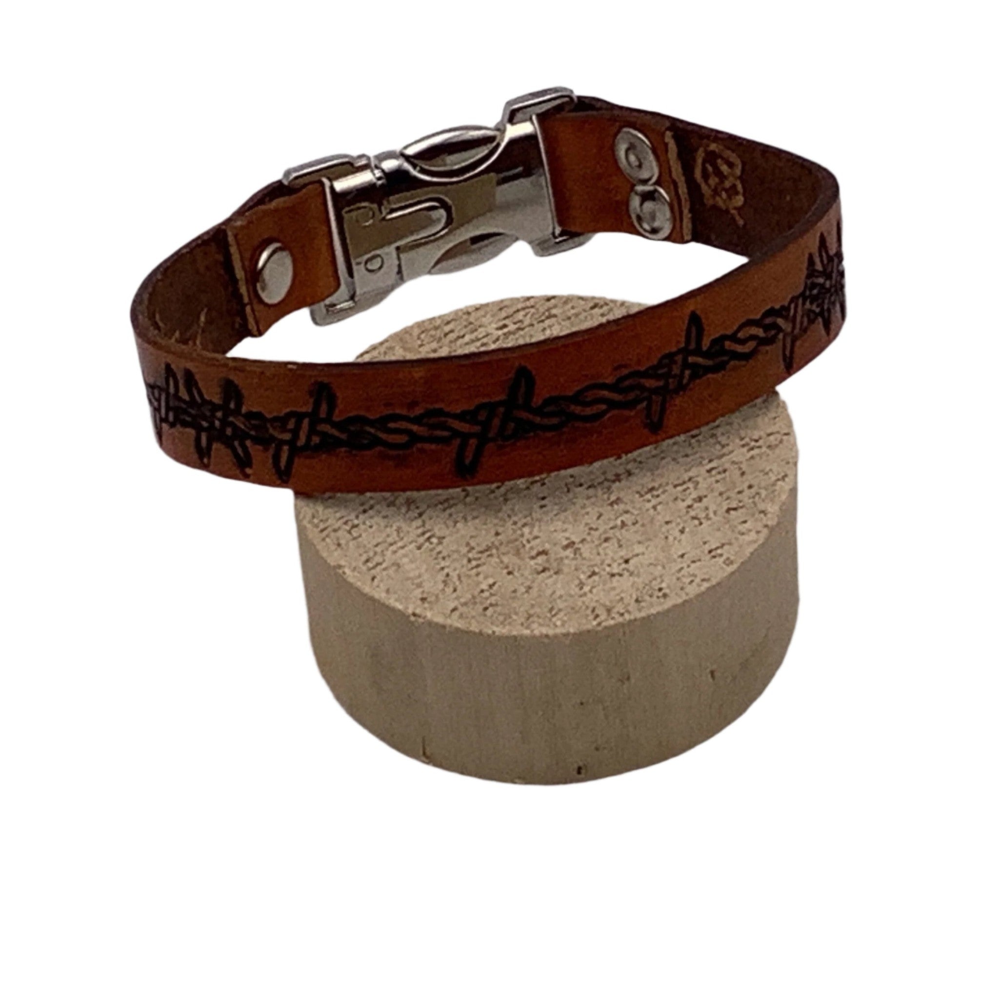 Brown leather bracelet with silver clasp on a cylindrical wooden block against a white background