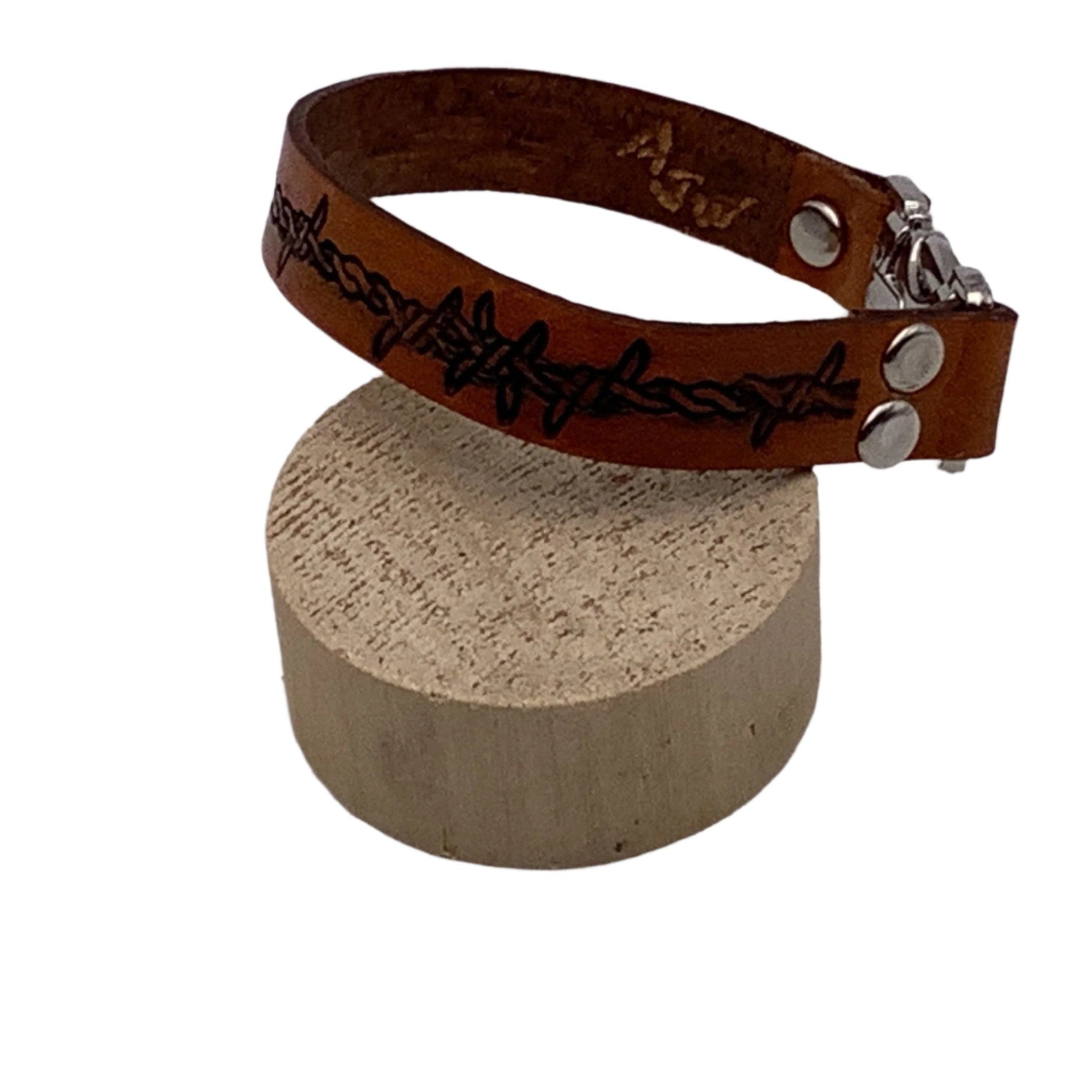A different side view of a leather bracelet with hand tooled barbed wire.