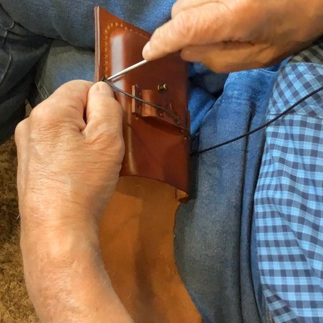 A leather worker making a phone holder.