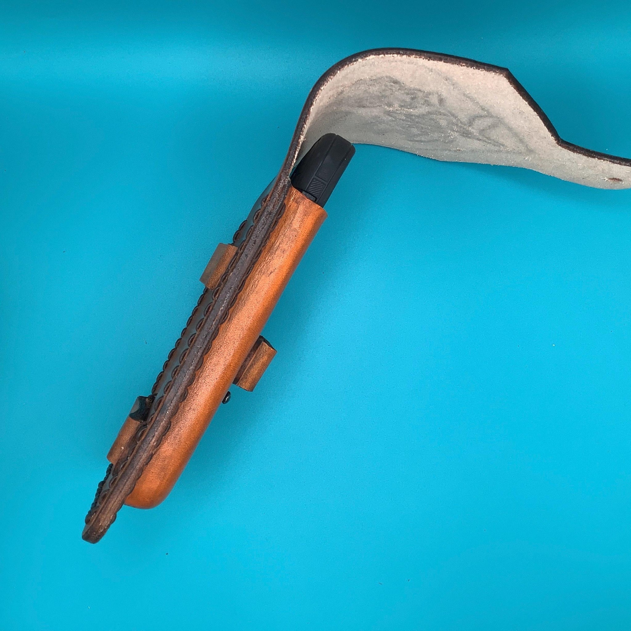 A side view of a tan leather saddle phone holder with roses in a heart.