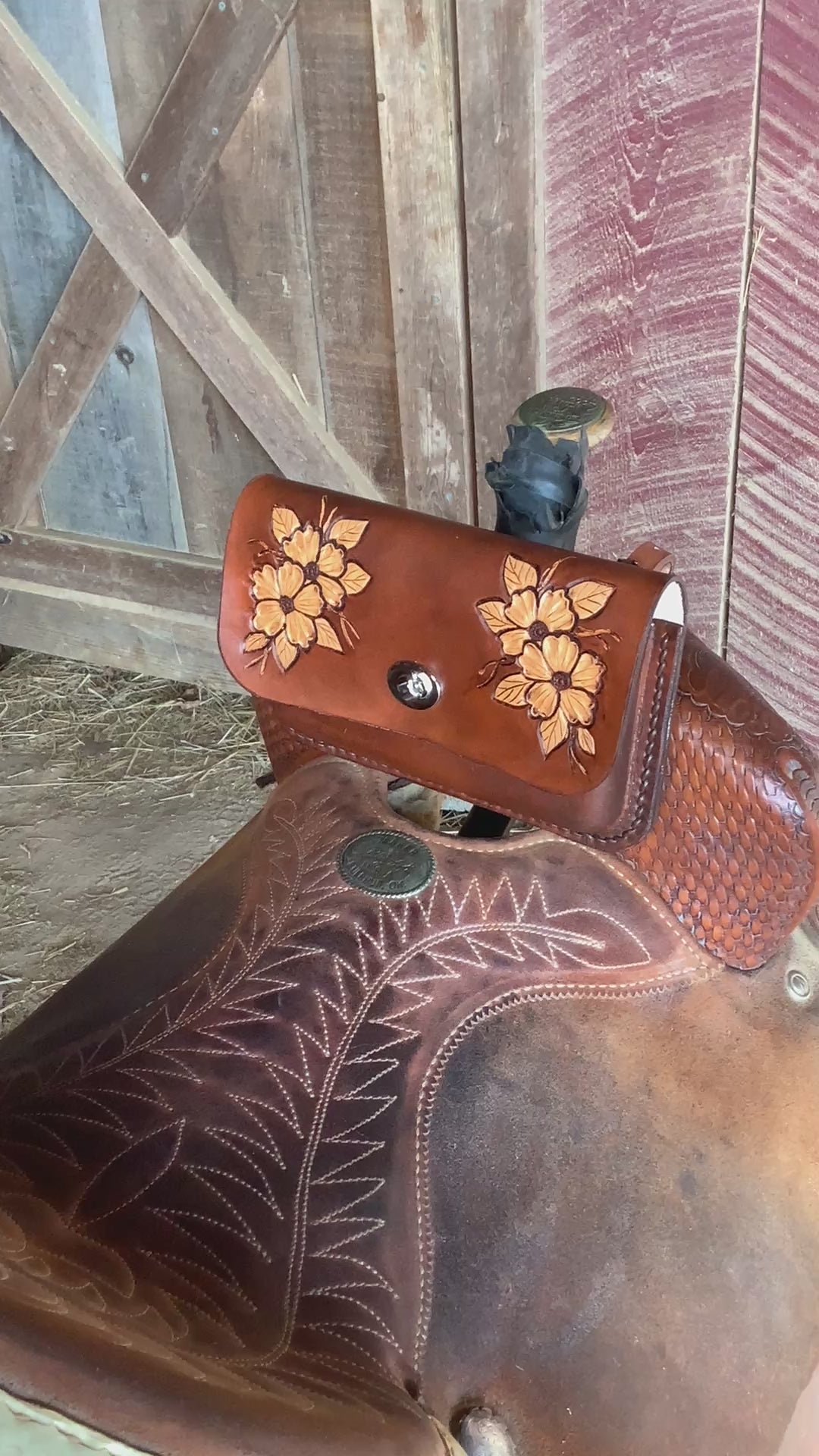 A person using a pommel bag on a western saddle to store a cellphone.
