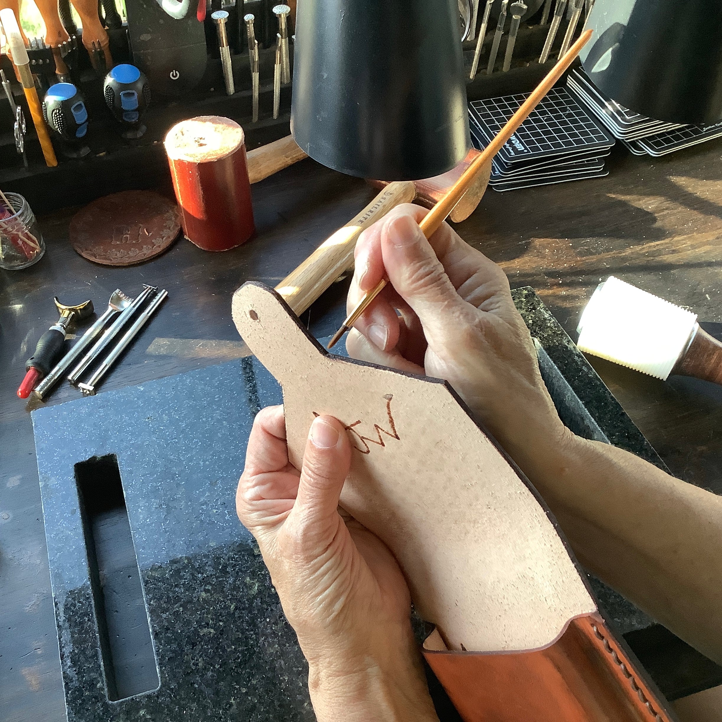 Rosa finishing the edge on hand tooled leather.