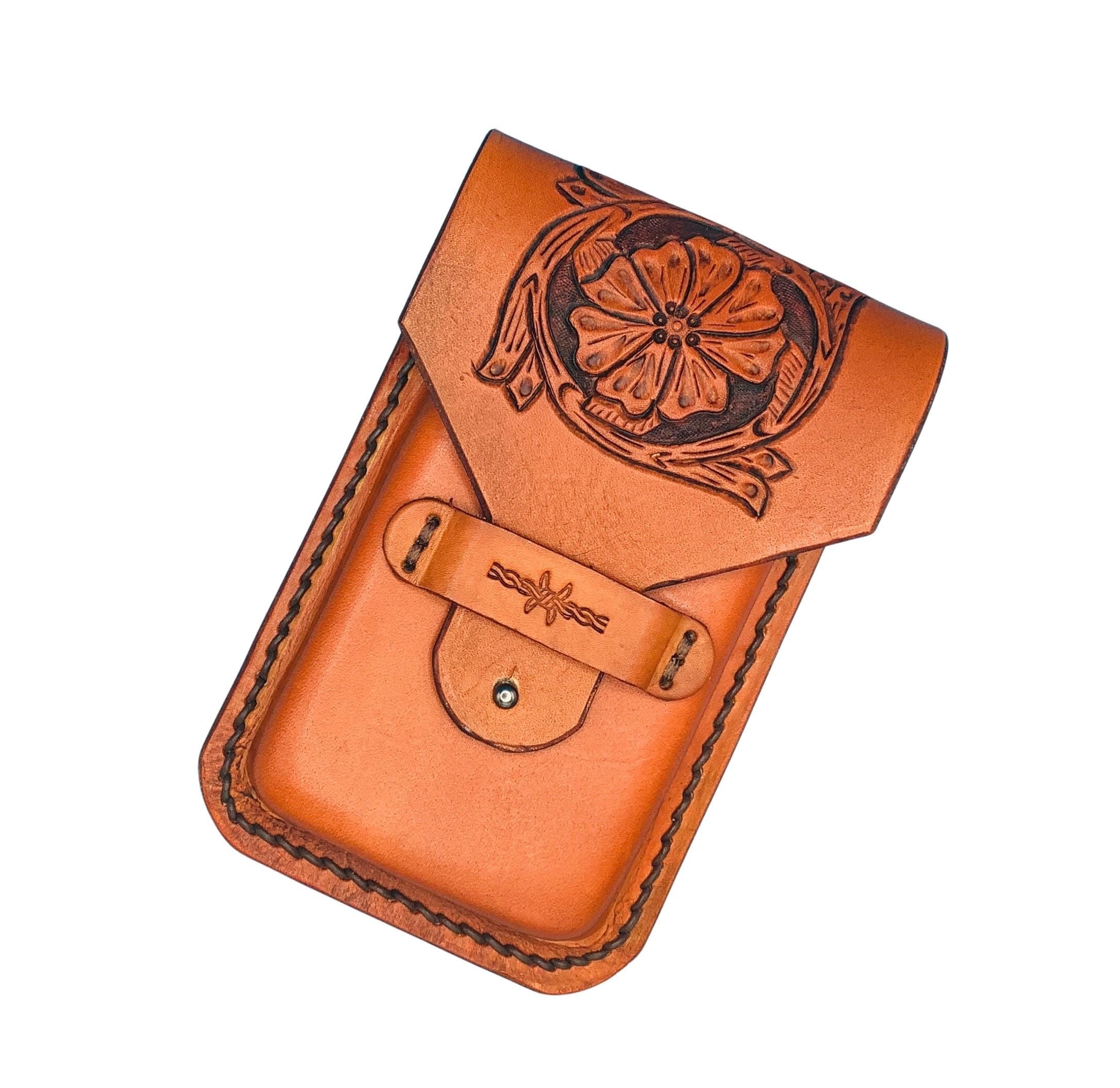A saddle tan leather phone holder for saddle billet with a hand tooled saddle flower pattern.