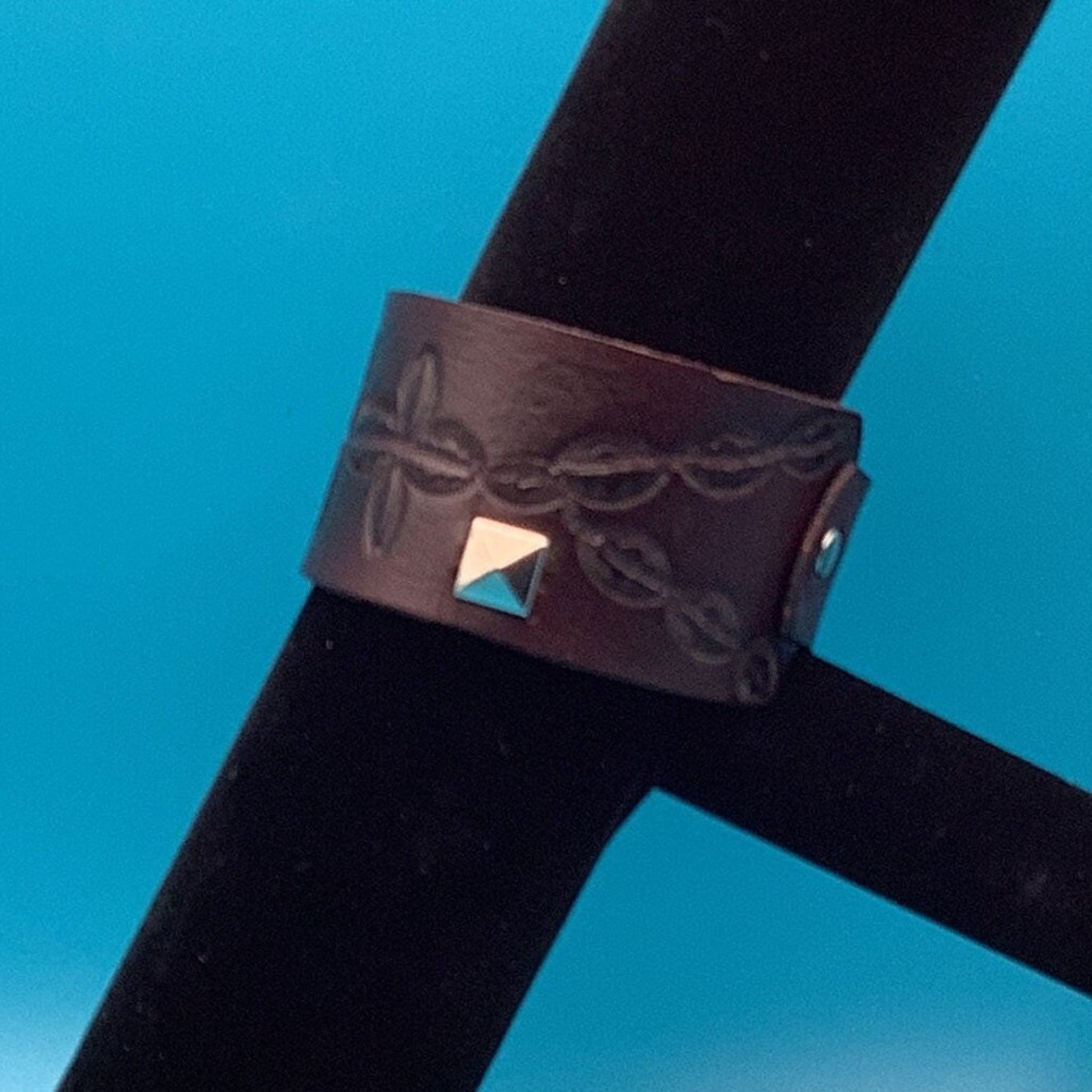 Western leather bracelet with studs on display bar showing adjustable fit.