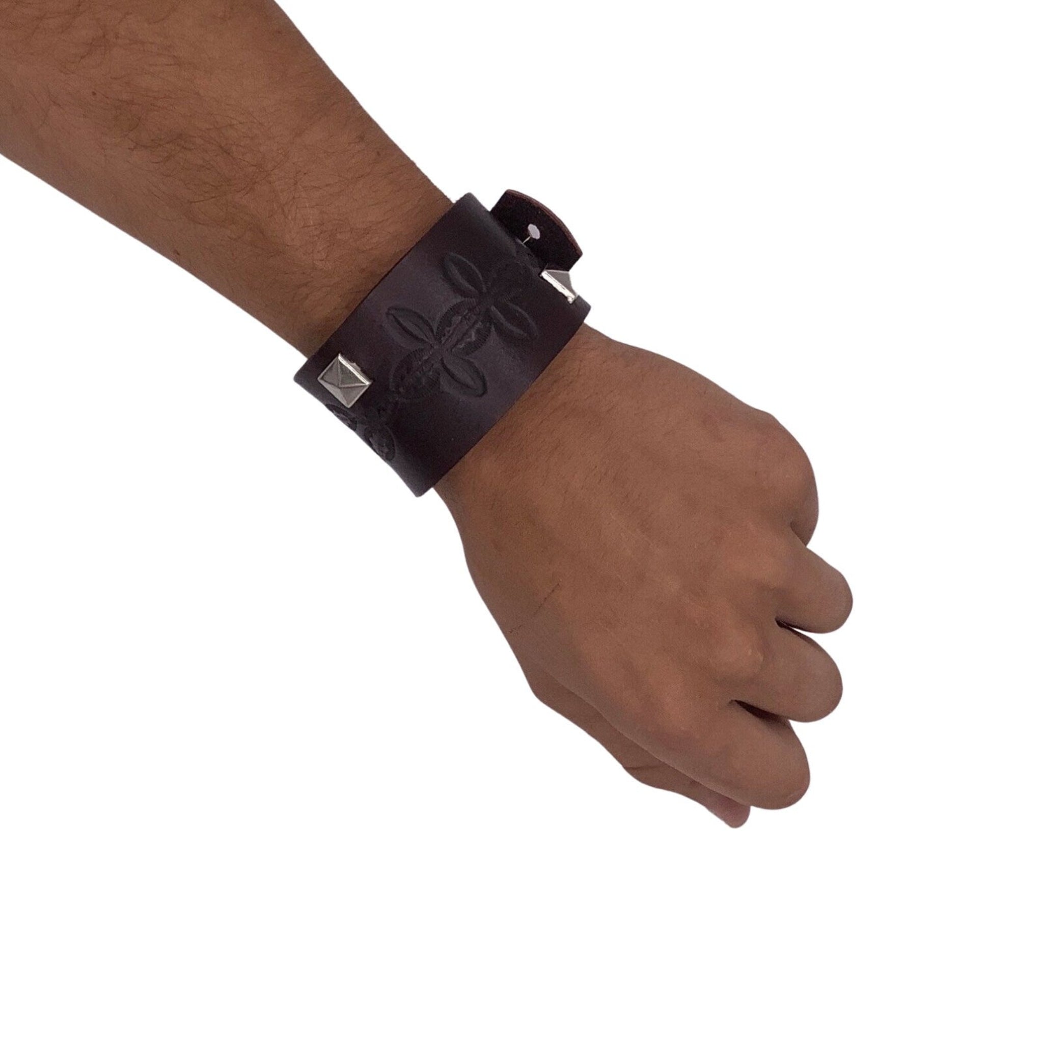 Wide leather bracelet with studs shown on a man's hand.
